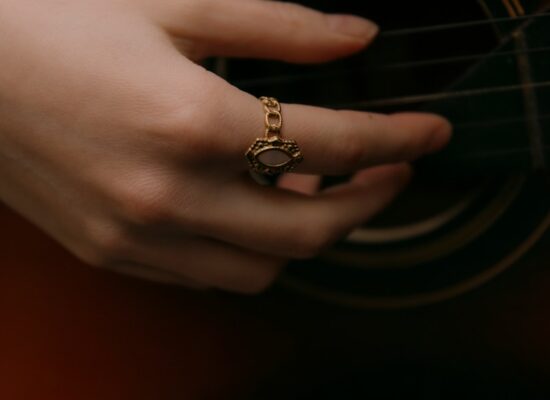 A hand plays the guitar with a cool ring.