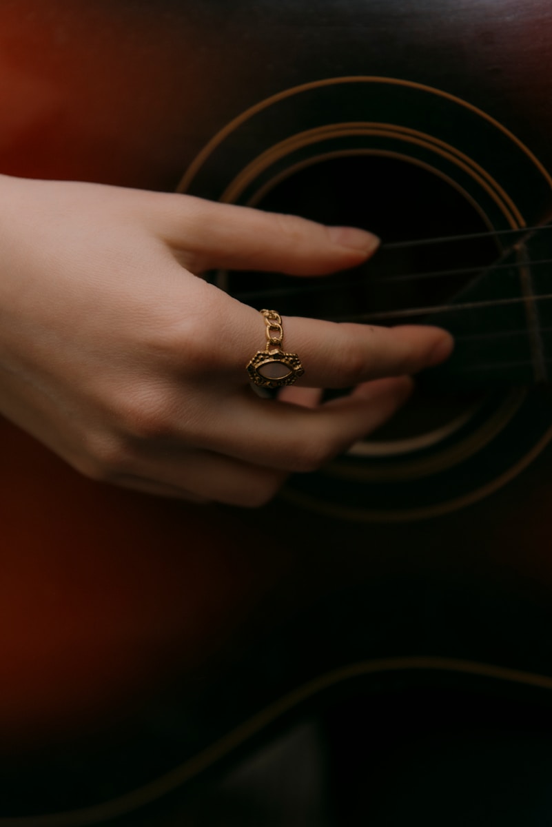A hand plays the guitar with a cool ring.